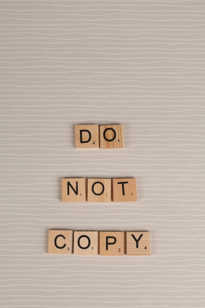 Scrabble tiles arranged as 'Do Not Copy' on a neutral background, conveying originality message.